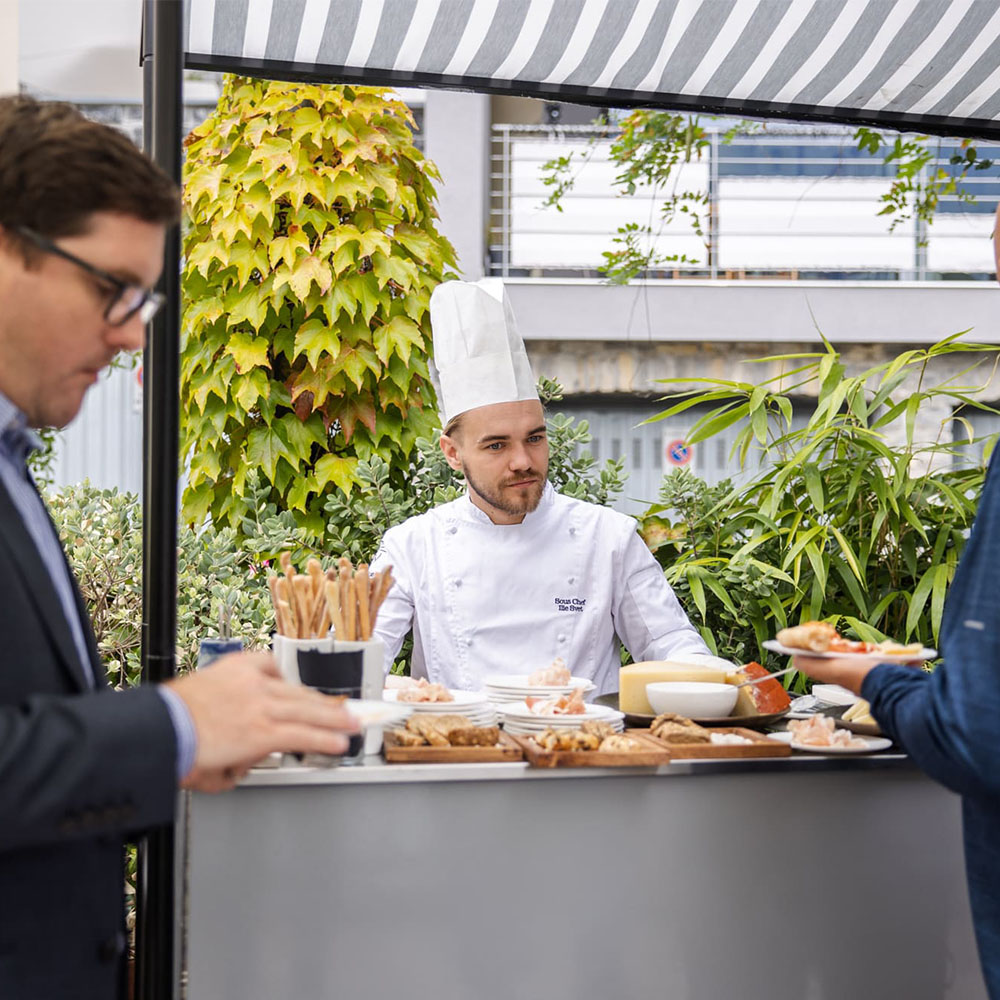 Chef dietro al bancone con ospiti che prendono da mangiare