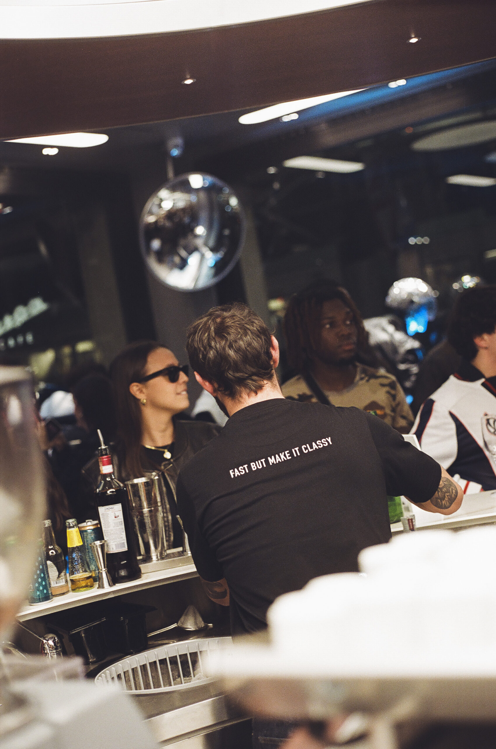 Barman di schiena con maglietta vespa che serve i cocktail