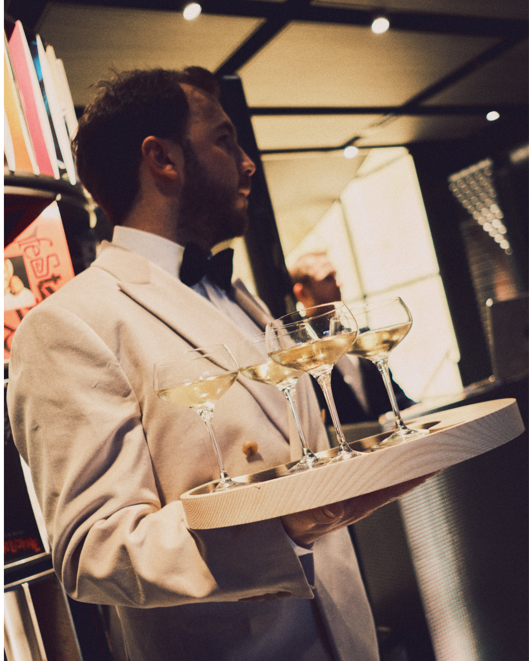 Cameriere con i mano un vassoio e dei calici di vino